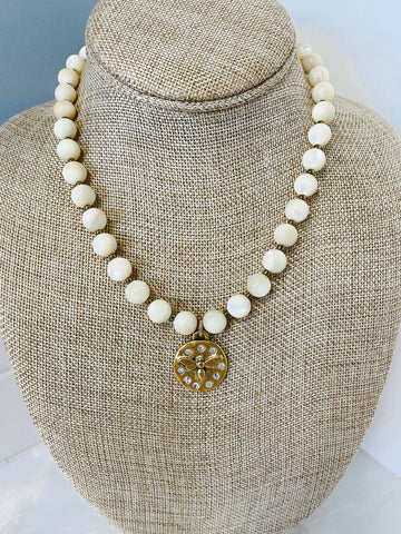 Bee pendant hangs from a mother of pearl bead necklace
