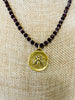 Gold plated bee pendant hangs from a faceted garnet necklace 